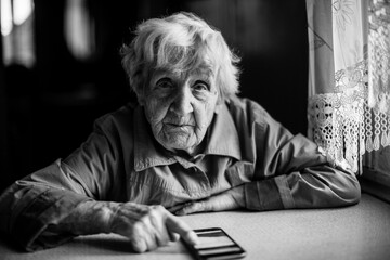 Wall Mural - An elderly woman with a smartphone. Black and white photo.