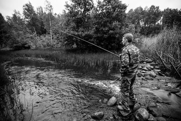 Wall Mural - Fisherman catching fish on the lake. Black and white photo.