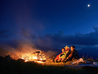 Wall Mural - tourist resting near outdoor bonfire in the night mountains.