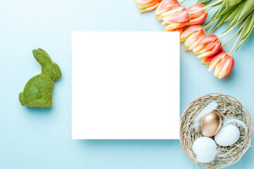 Wall Mural - Easter flower. Golden, white colour egg in basket with spring tulips, feathers on pastel blue background in Happy Easter decoration. Festive design with copy space.