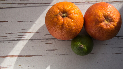 Two red oranges and a lime, close-up, copy space, pattern, rough shadows