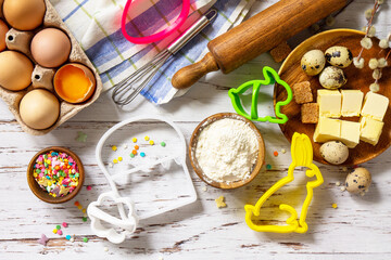 Wall Mural - Baking or cooking background frame. Ingredients, kitchen items for Easter festive baking. Kitchen utensils, flour, brown sugar, eggs, butter, confetti on rustic kitchen table. Flat lay. Top view.