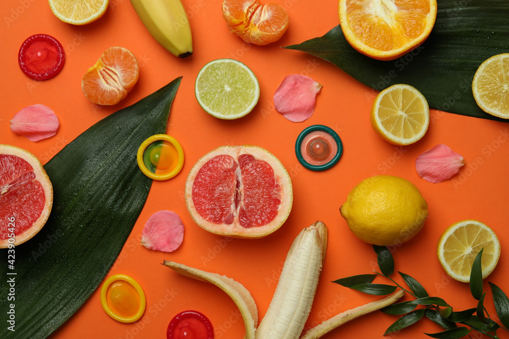 Sex concept with fruits and condoms on orange background - obrazy, fototapety, plakaty 