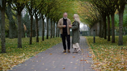 Wide shot of smiling happy couple having fun in beautiful foliage park. 