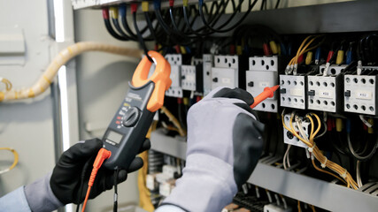 Electrical engineers test electrical installations and wiring on protective relays, measuring them with a multimeter.