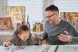 © boytsov - Happy attractive caucasian family creative art hobby and funny tome spending. Caring dad or babysitter drawing with colored pencils teaching child girl sitting at the table. High quality photo