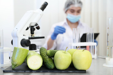 Wall Mural - fresh vegetables, fruits on table and scientist proceeding quality control in laboratory