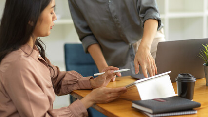 two office workers using digital tablet and brainstorming on their project in meeting room