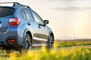 Landscape with blue off road car on gravel road. Traveling by auto, adventure in wildlife, expedition or extreme travel on a SUV automobile. Offroad 4x4 vehicle in field at sunrise.