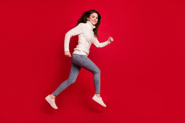 Poster - Full length photo of pretty sweet young woman dressed white sweater running fast jumping high isolated red color background