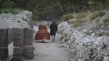 A Man And A Woman In 19th Century Suits Walk Along A Wide Trench