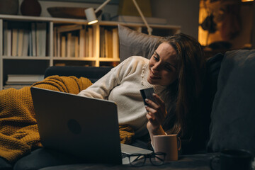 Wall Mural - woman relaxing on sofa at home and shopping online