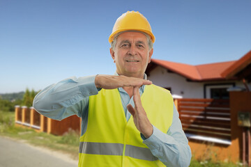 Wall Mural - Constructor with house background making pause timeout gesture