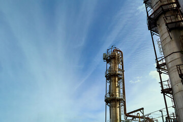 Oil refinery chemical plant bottom view with copyspace over blue evening sky with clouds background. Methanol production distillation refinery columns industrial background.