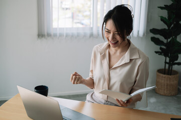 Excited Asian Businesswoman Celebrating Success At Workplace.