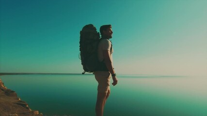 Wall Mural - the handsome man standing against the beautiful ocean. slow motion