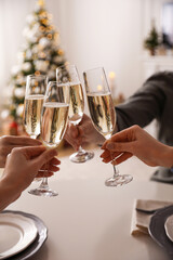 People clinking glasses with champagne at home, closeup