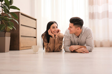 Wall Mural - Happy couple lying on warm floor at home. Heating system