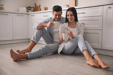 Sticker - Happy couple sitting on warm floor in kitchen. Heating system