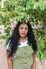 Curly haired girl standing next to a tree.