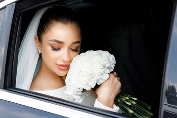 Wall Mural - Portrait of a beautiful young bride in the car. Close-up portrait of a pretty bride in a car window