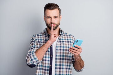 Sticker - Portrait of mysterious attractive bearded guy using gadget showing shh sign isolated over gray pastel color background