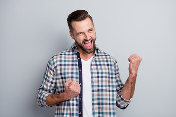 Poster - Photo of young attractive handsome crazy smiling positive excited man hold fists in victory isolated on grey color background