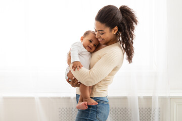 loving african mother holding baby toddler in arms standing indoors