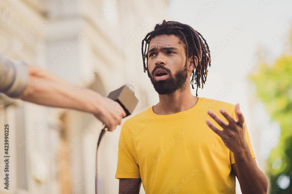 Photo portrait of young man giving interview on street speaking on camera for press television - obrazy, fototapety, plakaty 