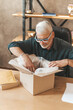 © Andrii Zastrozhnov - Damaged package. Disgruntled mature male shopper opens a box at home. Wrong delivery, return of goods.