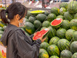 © Quang - Asian woman wearing mask and choosing watermelon at groceries store