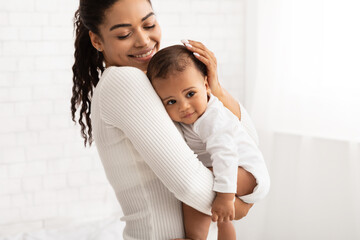 Wall Mural - Happy African Mom Holding Baby Toddler Standing Indoors