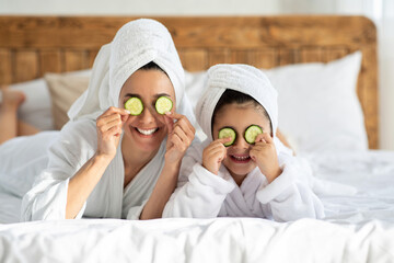 Wall Mural - Happy family mother and daughter with cucumber circles on eyes