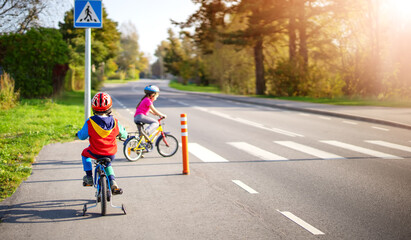 cute children riding on bicycles on asphalt road in summer.