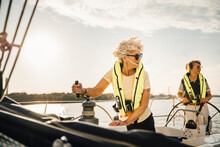 Female Friends Looking Away While Sailing In Boat Against Sky