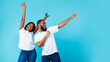 © Prostock-studio - Smiling black couple celebrating win, pointing aside at copy space