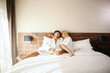 © Dusan Petkovic - Mornings at the hotel. A smiling beautiful blonde and a handsome man are resting in the bed of a hotel room and making beautiful love memories. Love, emotional, lovers. White empty copy space wall
