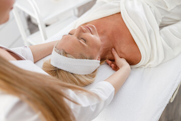 senior female is lying on back, getting face lifting massage. facial massage beauty treatment. welln