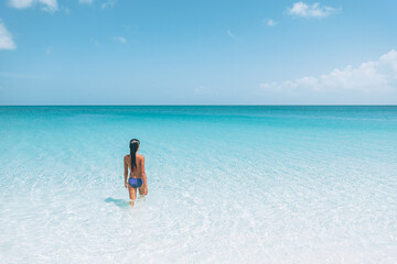 Wall Mural - Beach travel Caribbean vacation. Bikini woman relaxing sunbathing in water tanning enjoying sun. Winter holidays.