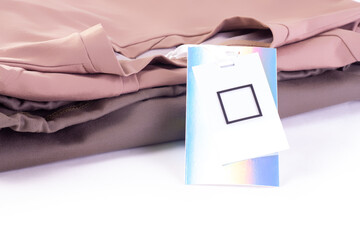 Wall Mural - macro mock up empty paper metallic shiny iridescent label or tag on a stack of T shirts or hoodies.