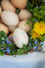  Beautiful spring bouquet in a wooden basket with Easter painted eggs, eggs with cute faces. Colorful greeting card for the Easter holiday.