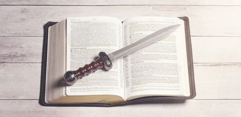 Wall Mural - Bible with a Sword on a Bright White Wooden Table