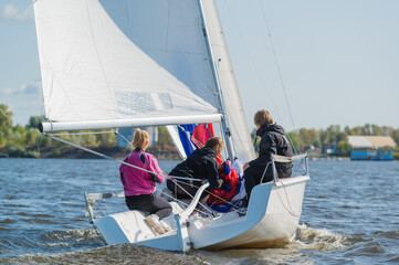 Dad and his two daughters went out on a yacht on the river to sail along the city and teach the girls to conduct a sports yacht.