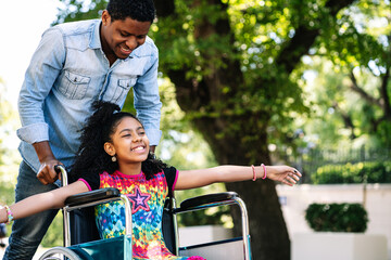 Little girl in a wheelchair enjoying a walk with her father.