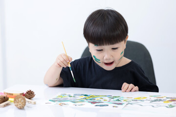 Happy little Asian kid at the table draw with water color Learning and education of kid.