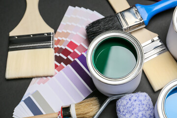 Cans of paints and tools on dark background, closeup