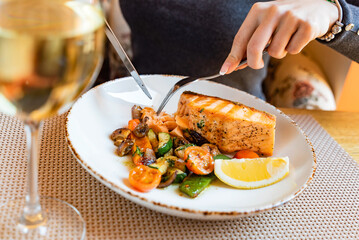 woman eating salmon steak with roasted vegetables