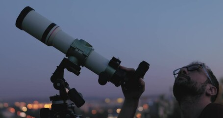 Wall Mural - astronomer with a telescope watching at the stars and moon with blurred city lights in the backgroun
