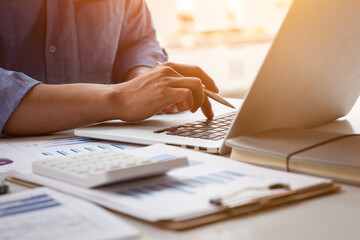 close up business man using calculator and laptop for do math finance on wooden desk, tax, accountin