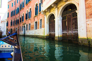 Beautiful narrow canal with gondolas and small boats and historical buildings in Venice, Italy